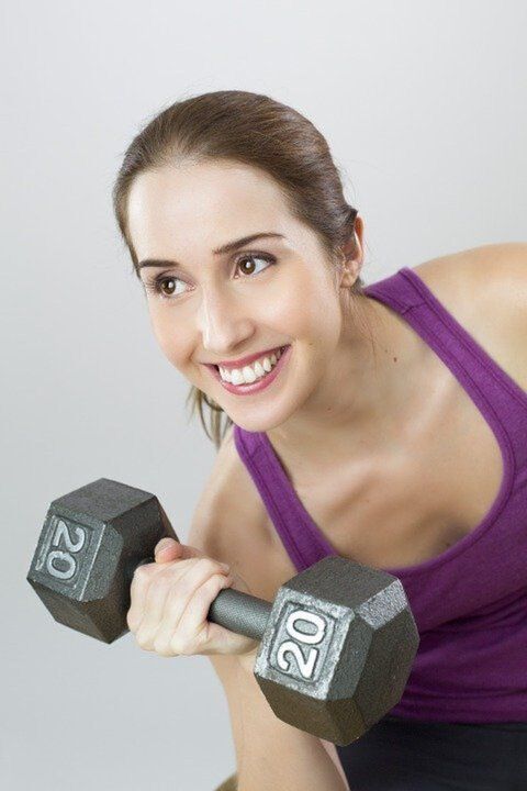 a girl with a dumbbell does an exercise to lose weight